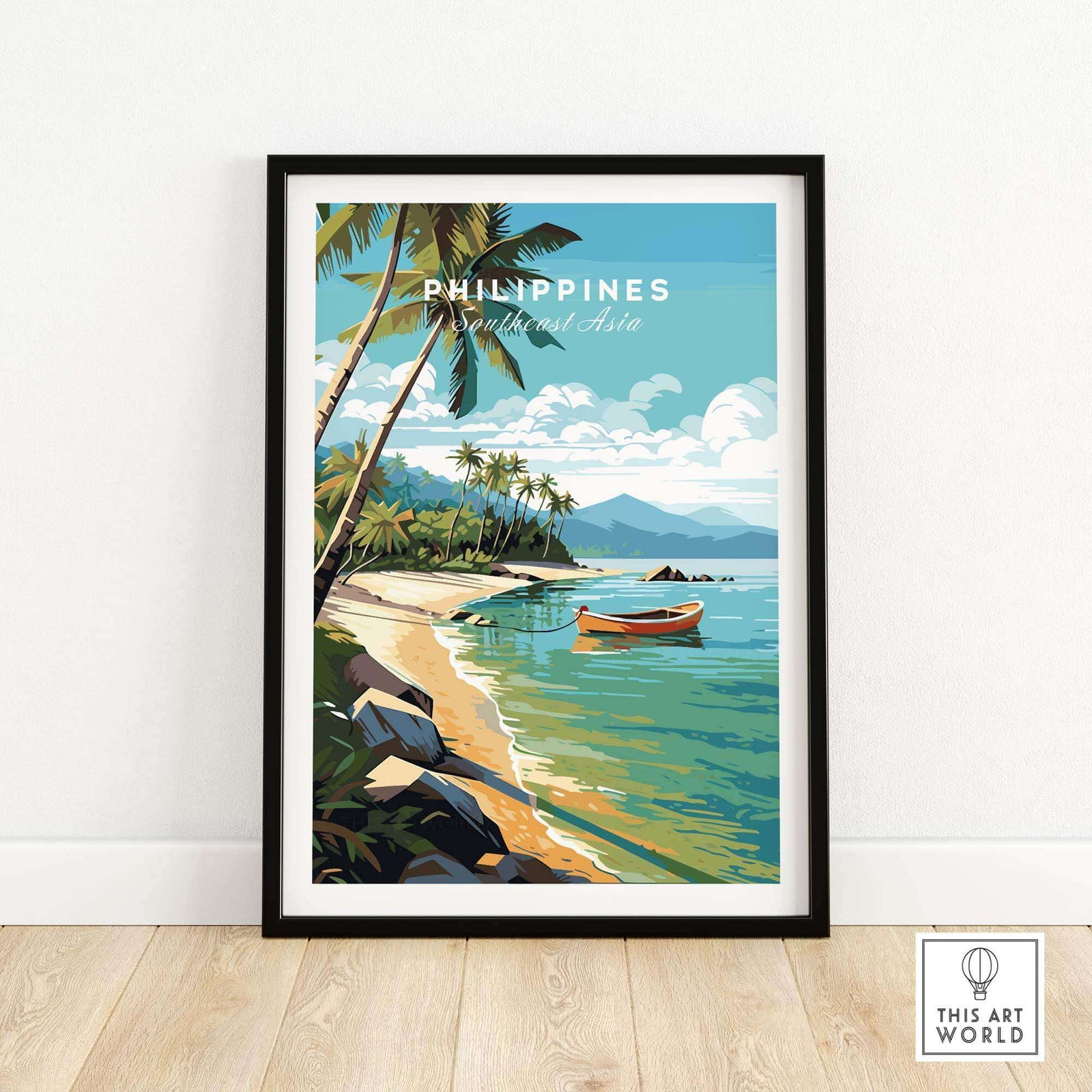 A framed travel poster of the Philippines showing a tropical beach with a boat in a black frame on a wooden floor. 