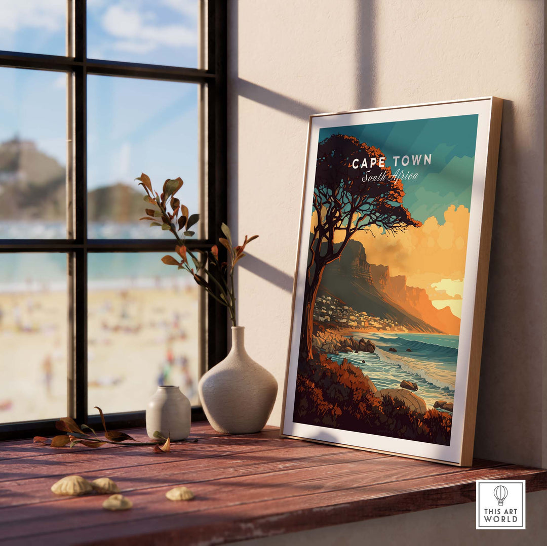 Cape Town print featuring Camps Bay shore, displayed elegantly beside a window in a cozy interior setting.