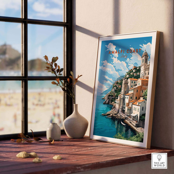 Amalfi Coast Italy travel poster print displayed in a sunlit room with a beach view, showcasing pastel colors and Italian landscape.