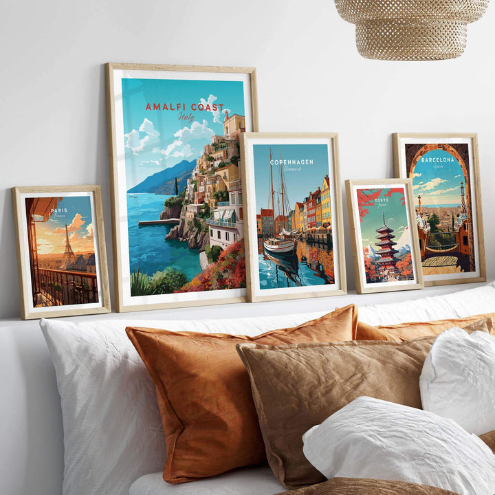 Amalfi Coast Travel Poster Print displayed alongside other city art prints on a cozy bed with cushions.