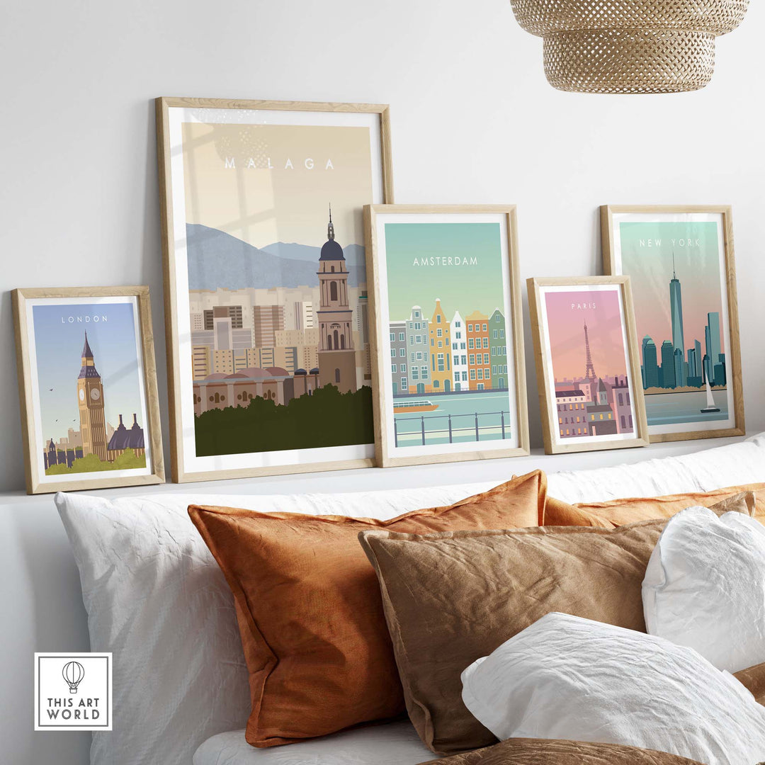 Framed Malaga travel poster print among other city art prints on a modern decor sofa setting.