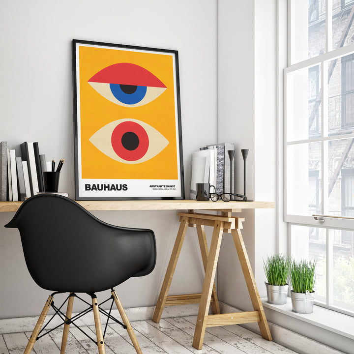 Bauhaus Exhibition Prints Abstract Eyes poster in a modern workspace with black chair and plants.