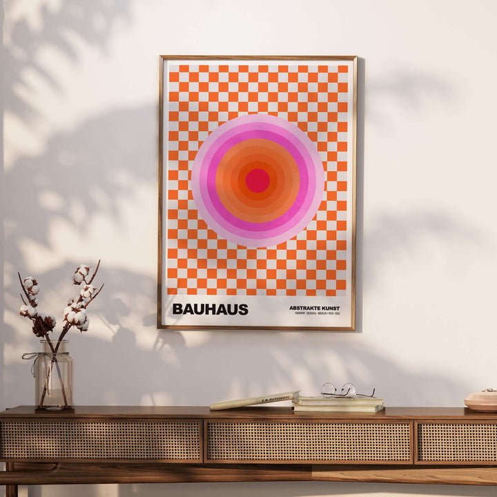 Bauhaus exhibition print featuring pink circles on an orange checkerboard background, displayed in a stylish setting.