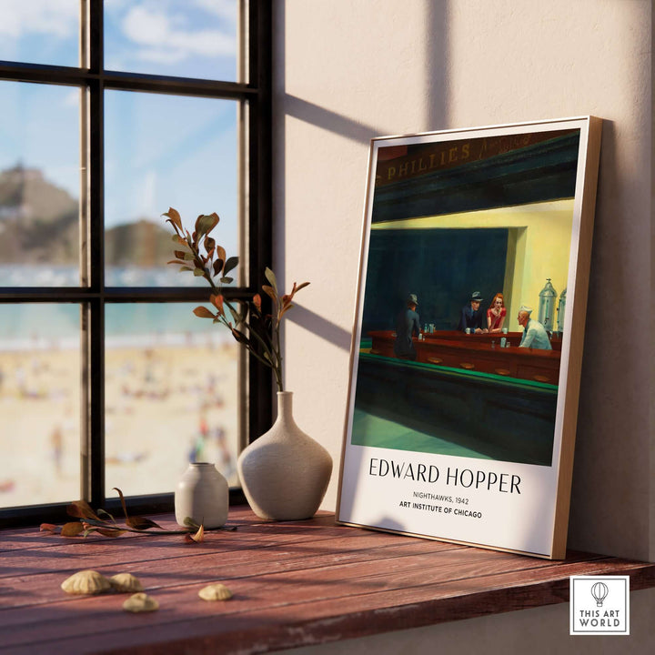 Edward Hopper Nighthawks 1942 art print displayed by a window with a beach view, showcasing urban loneliness theme.