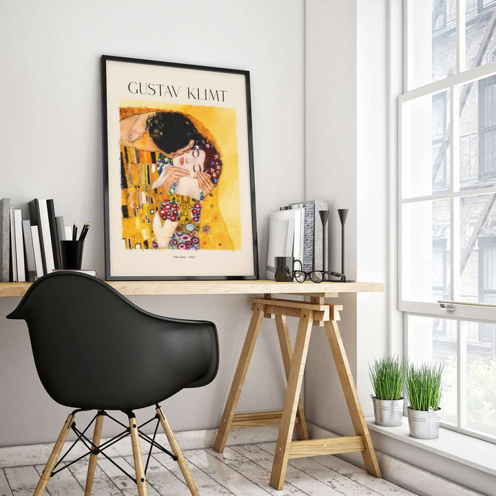 Gustav Klimt art print 'The Kiss' displayed in a modern workspace with a stylish chair and natural light.
