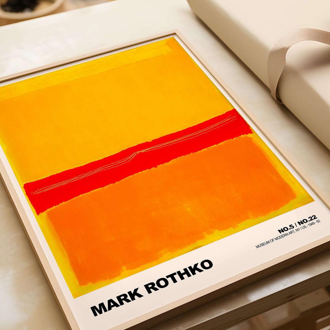 Mark Rothko No 5 No 22 abstract expressionist print in red, orange, and yellow framed poster on table.