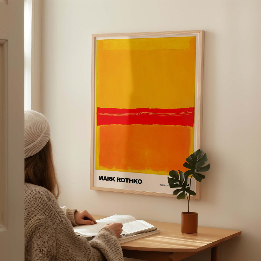 Mark Rothko No 5 No 22 abstract print in vibrant red, orange, and yellow, displayed on wall with viewer reading beside it.