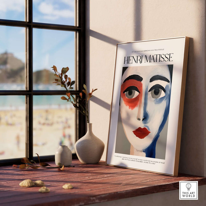 Matisse art print featuring an abstract face portrait in bold colors displayed on a windowsill with a beach view.