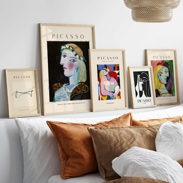 Framed Picasso art prints displayed on a shelf with stylish cushions and warm decor.