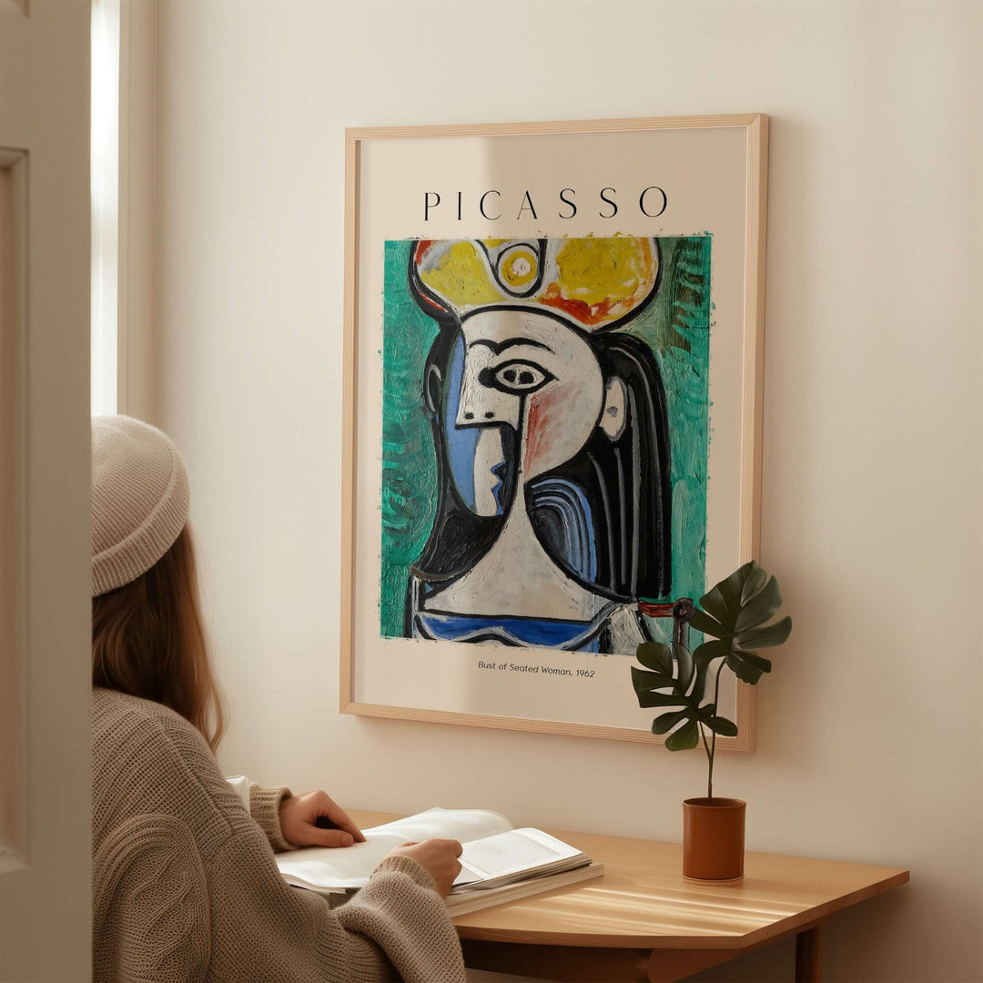 Woman reading with Picasso Bust of Seated Woman 1962 art print poster on wall, featuring vibrant colors and Cubist style.
