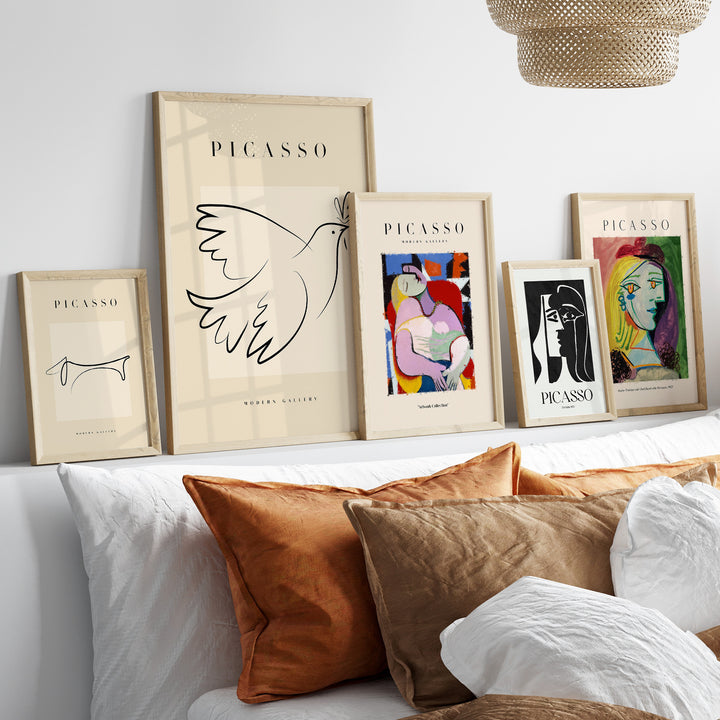 A collection of Picasso-inspired line art prints and minimalist posters displayed above a sofa with decorative pillows.