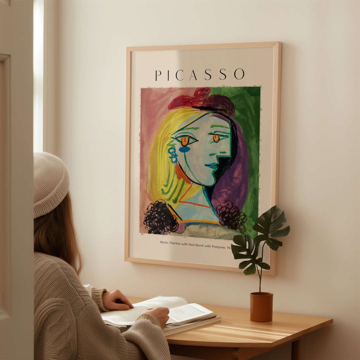 Woman admiring Picasso's 'Marie-Thérèse with Red Beret' art print in a cozy setting.