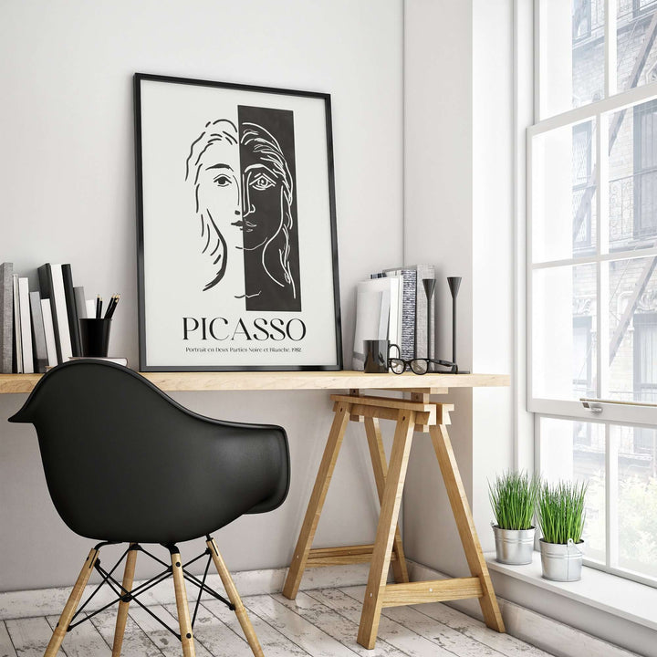 Picasso black and white split face art print displayed on a desk in a modern workspace.