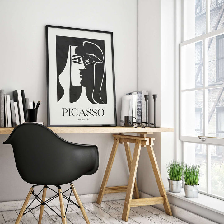Picasso The Kiss 1979 black and white abstract profile art print framed on a wall in a modern workspace.
