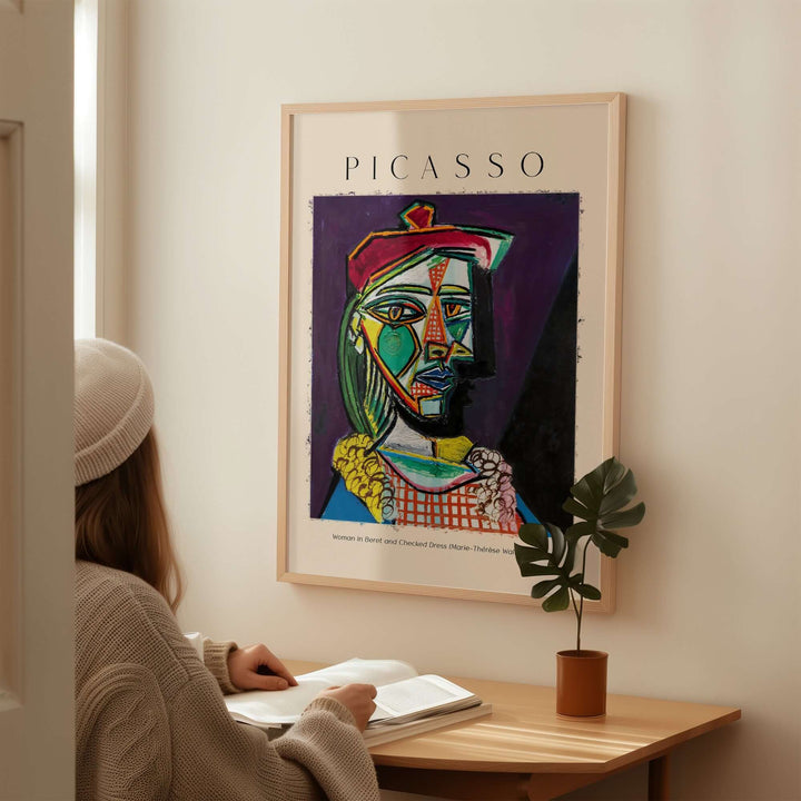 Woman sitting at desk admiring Picasso 1937 Cubist portrait poster of Marie-Thérèse in beret and checked dress.