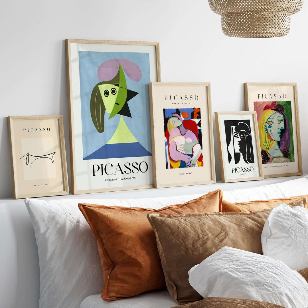 Collection of framed Picasso art prints displayed on a shelf, featuring abstract portraits and geometric shapes.