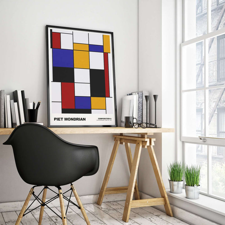 Piet Mondrian Composition A abstract art print displayed in a modern workspace, featuring geometric shapes and bold colors.