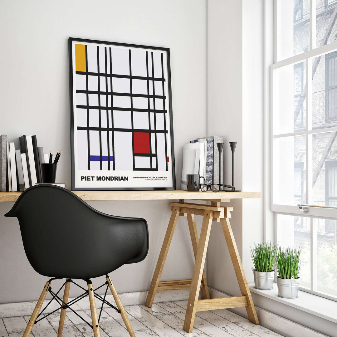 Piet Mondrian abstract art print featuring yellow, blue, and red on a grid in a modern workspace.