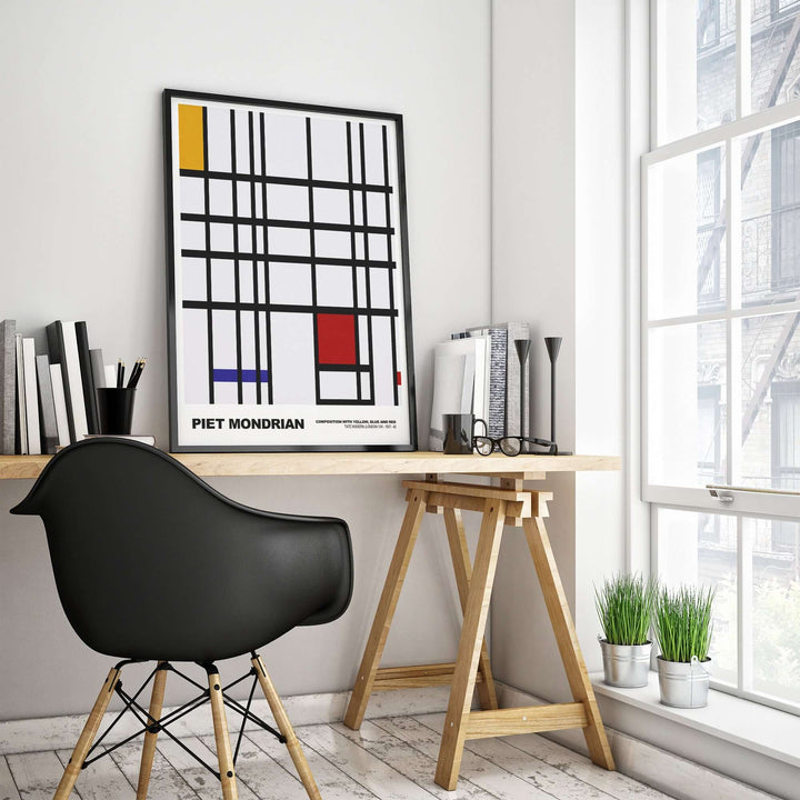 Piet Mondrian abstract art print featuring yellow, blue, and red on a grid in a modern workspace.
