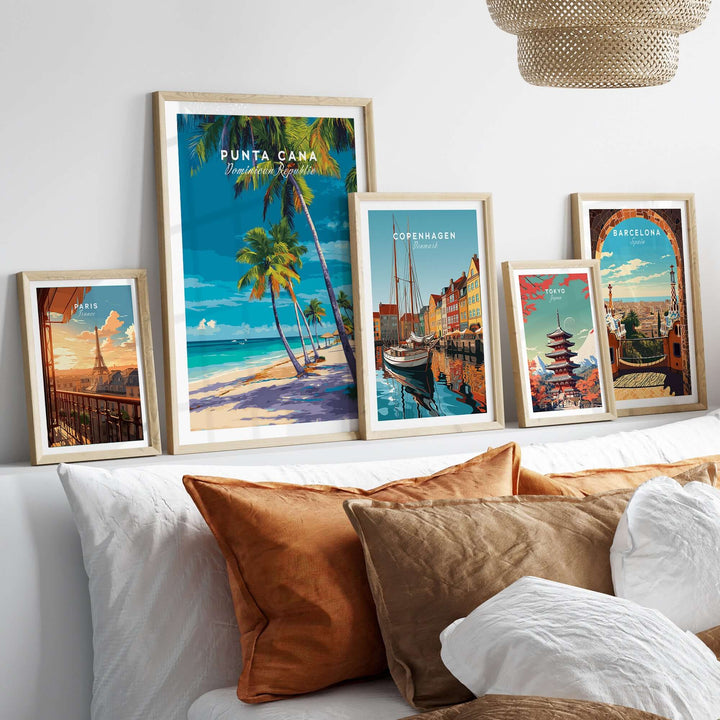 Punta Cana beach poster among framed travel art on a cozy bed with decorative pillows.