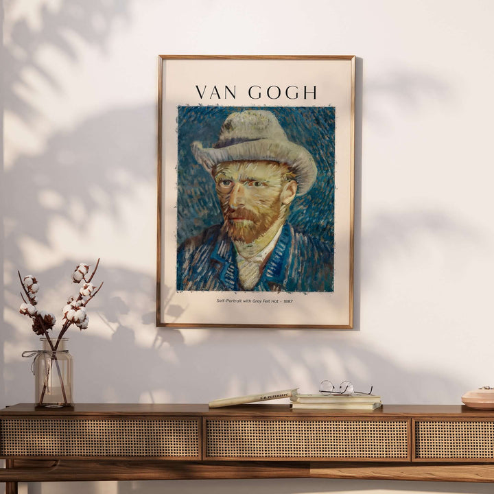 Vincent van Gogh Self Portrait with Grey Felt Hat art print displayed on a wall above a wooden table.