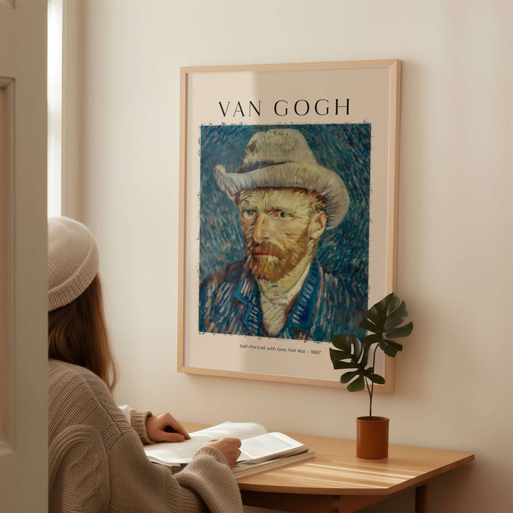 Vincent van Gogh Self Portrait with Grey Felt Hat art print framed on wall, woman seated at table reading.