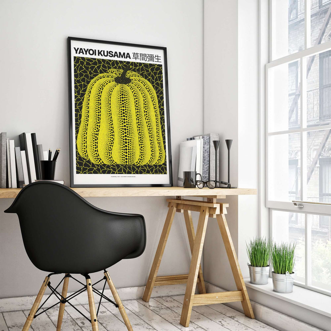 Yayoi Kusama Yellow Black Pumpkin art print poster in modern workspace with stylish decor and plants.