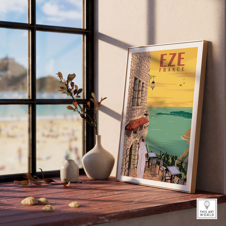 Eze France poster print wall art on a wooden table with a beach view, perfect for travel enthusiasts.