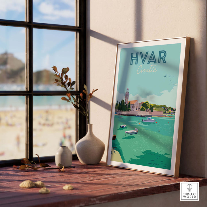 Framed Hvar Croatia travel poster wall art displayed in a sunlit room with a view of the beach.