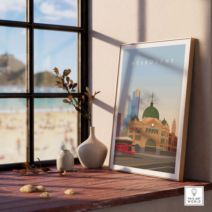 Melbourne Wall Art Print framed on a table with a vase, featuring iconic buildings and a beach view.