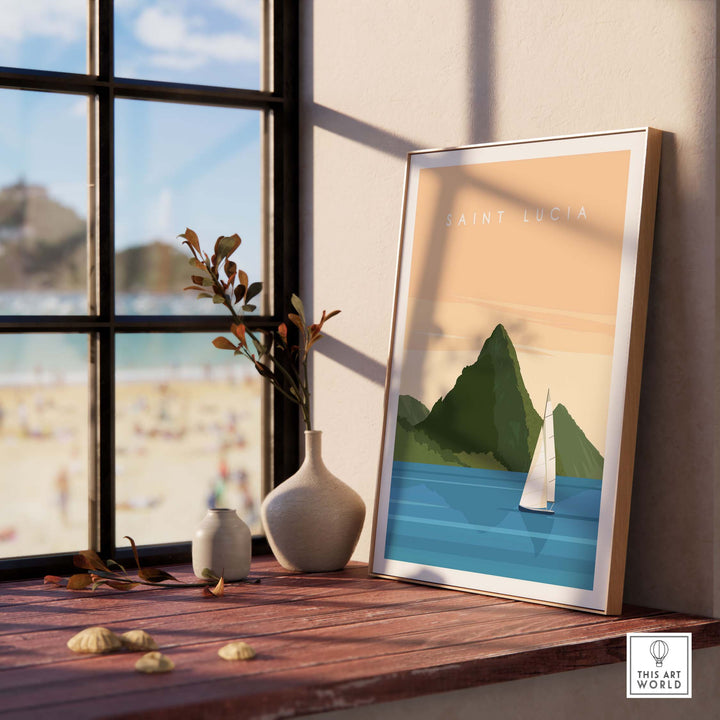 Saint Lucia wall art print featuring mountains and a sailboat, framed on a windowsill with a beach backdrop.