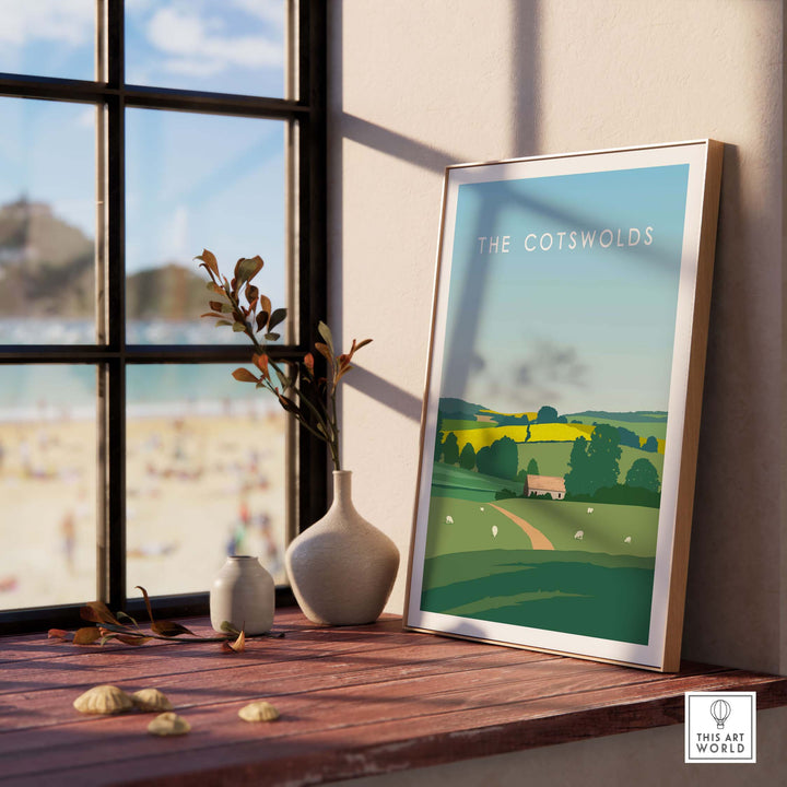 The Cotswolds poster print displayed indoors, featuring a serene landscape with rolling hills and a quaint cottage.
