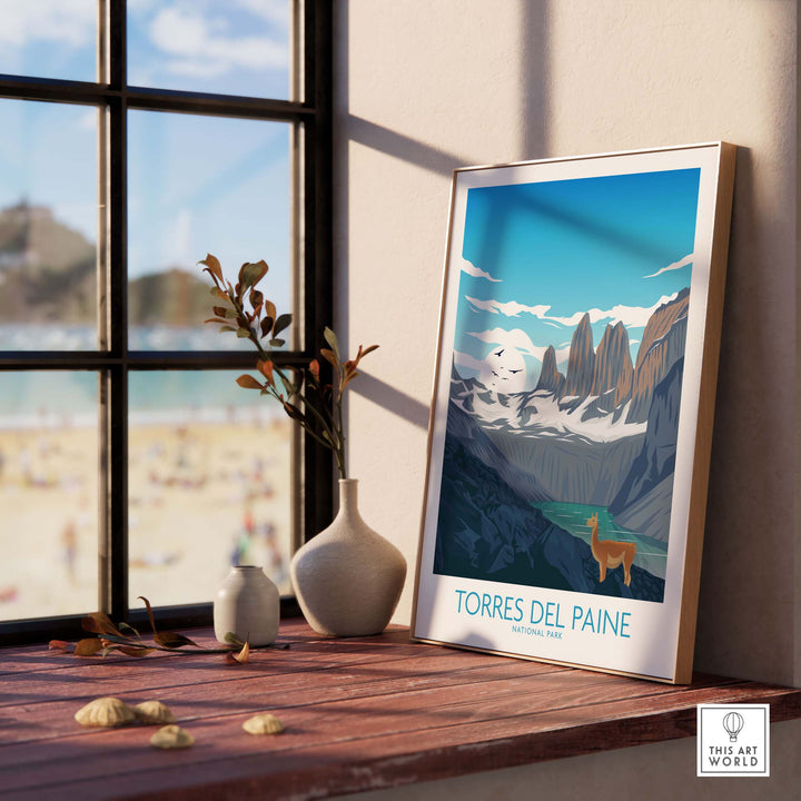 Torres del Paine Chile poster framed on a table by a window, showcasing vintage travel art and nature inspiration.
