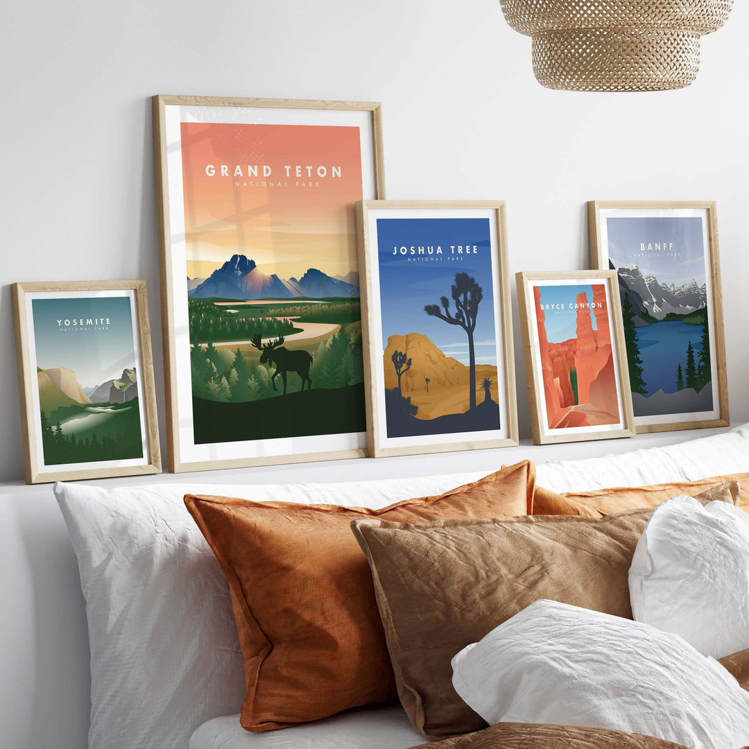 Framed art prints of Grand Teton, Joshua Tree, and other national parks on a stylish wall above a cozy bed.