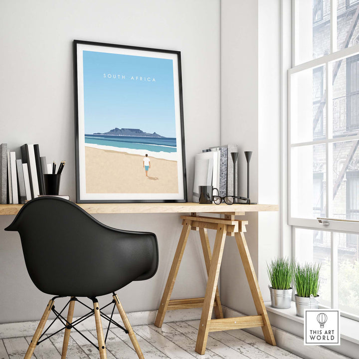 South Africa travel poster print displayed in a stylish office with minimalist decor and a view of a beach.