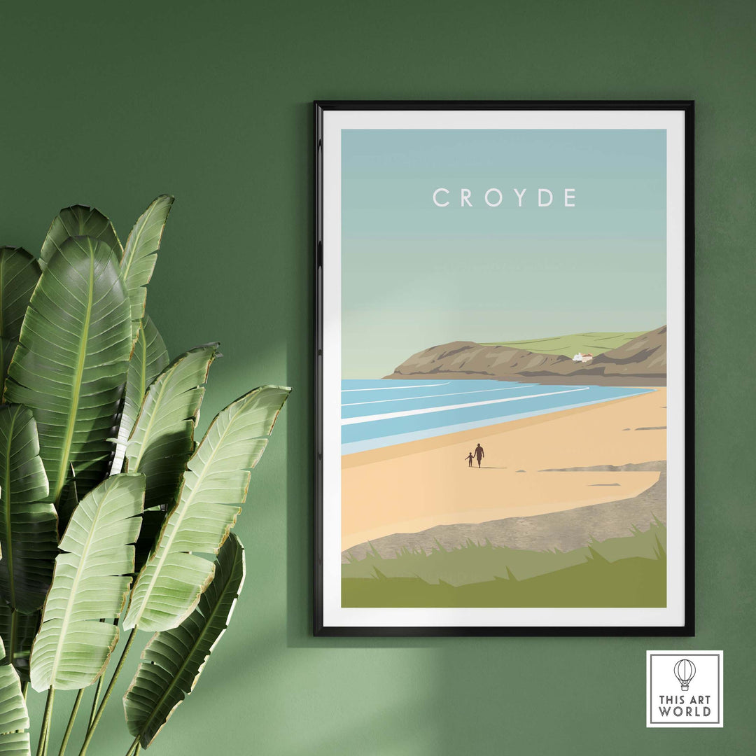 Croyde Poster Print Wall Art featuring a beach scene, framed on a green wall with plants, perfect for home decor.