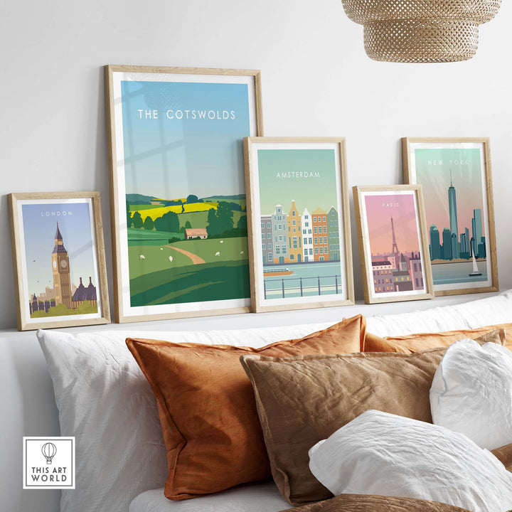 Framed travel poster prints of The Cotswolds, London, Amsterdam, Paris, and New York on a stylish couch.