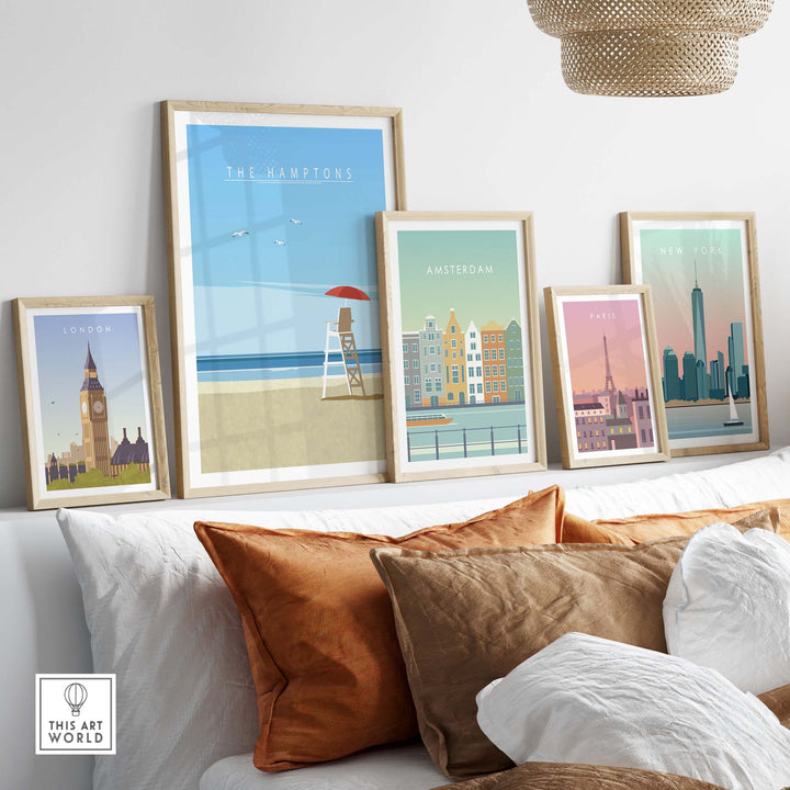 Framed travel posters featuring The Hamptons, London, Amsterdam, and Paris on a stylish wall above cozy cushions.