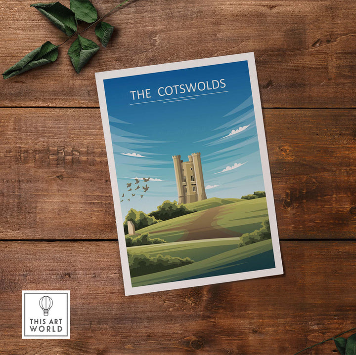Minimalist travel poster of The Cotswolds featuring green hills and a castle on a wooden surface.