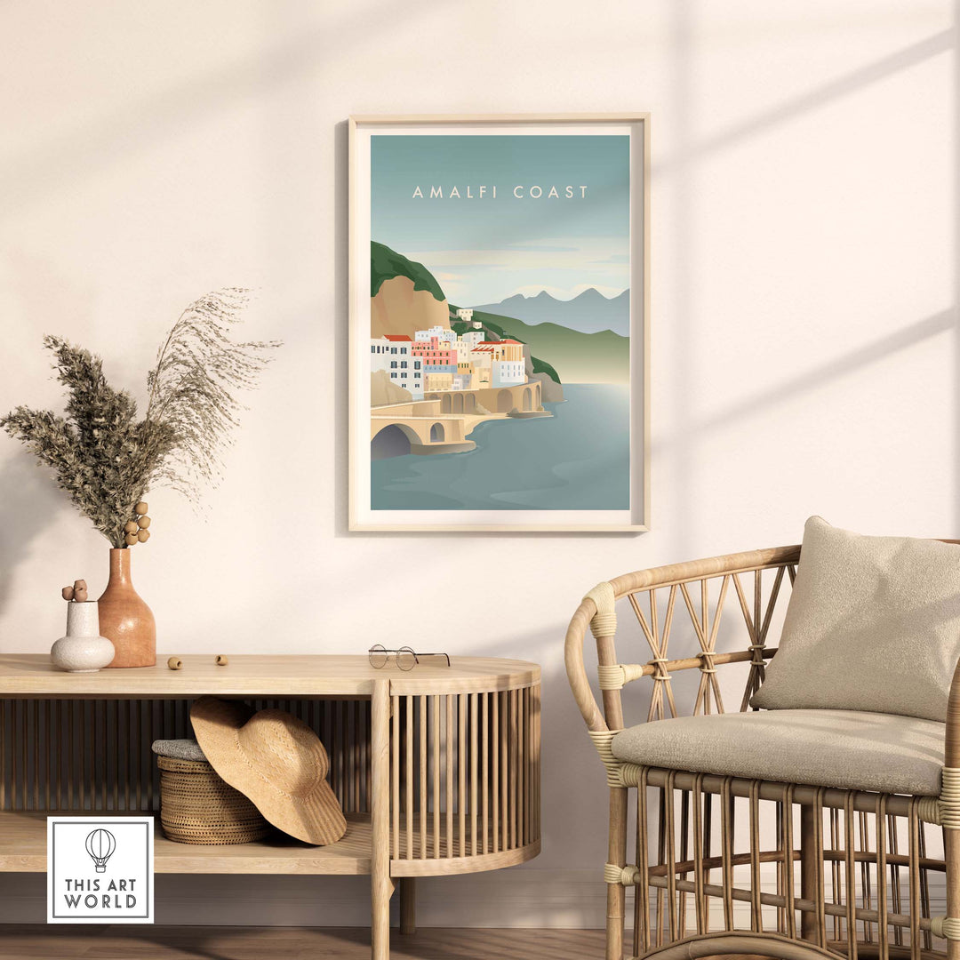 Minimalist Amalfi Coast print framed on wall above a stylish rattan chair and decorative plant.