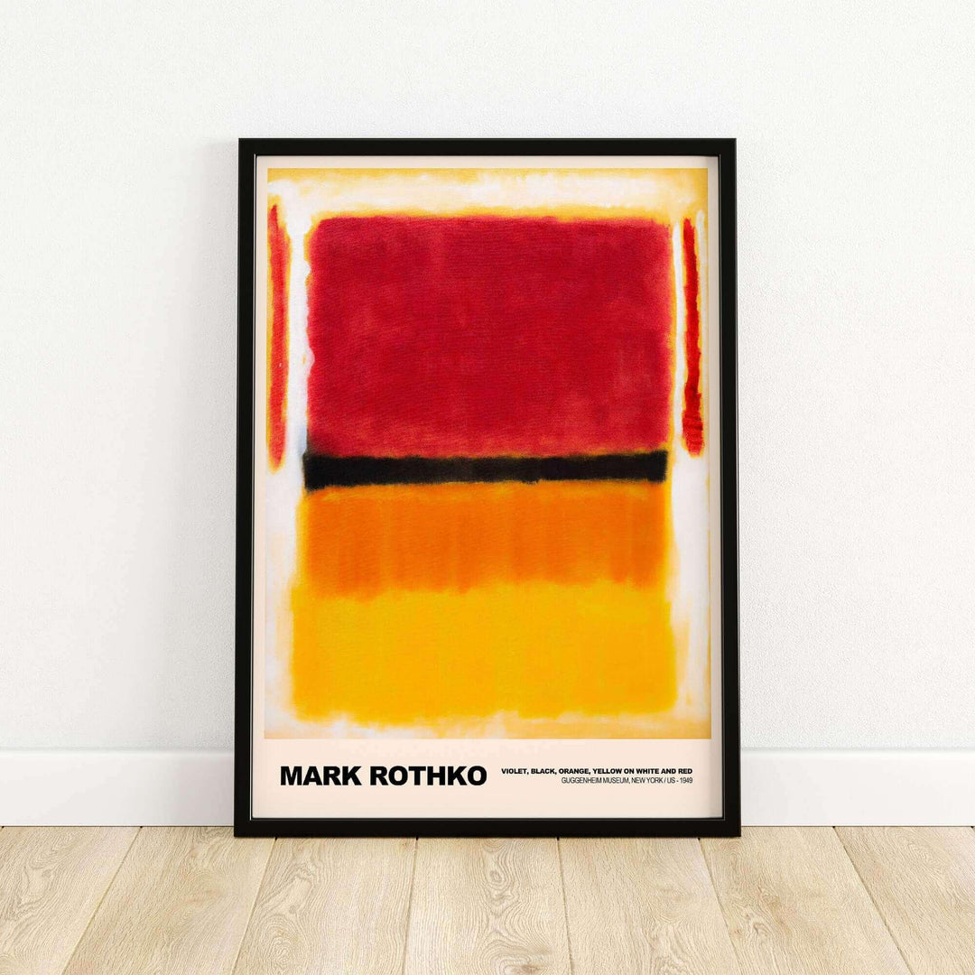 Framed Mark Rothko abstract art print with red, orange, and yellow color blocks, leaning against a white wall on a wooden floor.