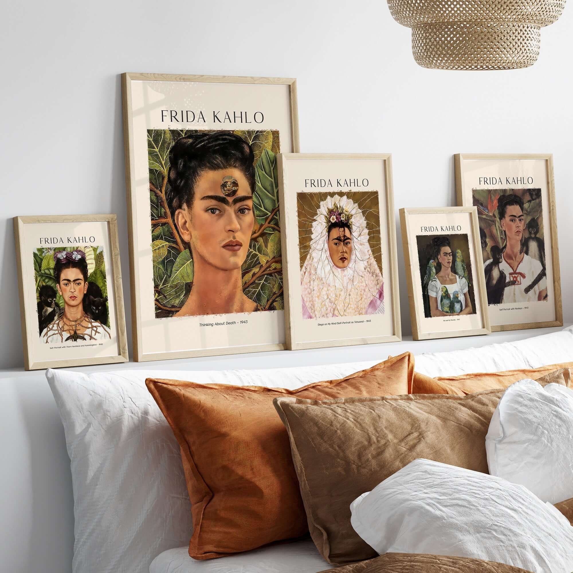 Frida Kahlo art prints displayed on a wall above a bed with decorative pillows, showcasing iconic self-portraits.