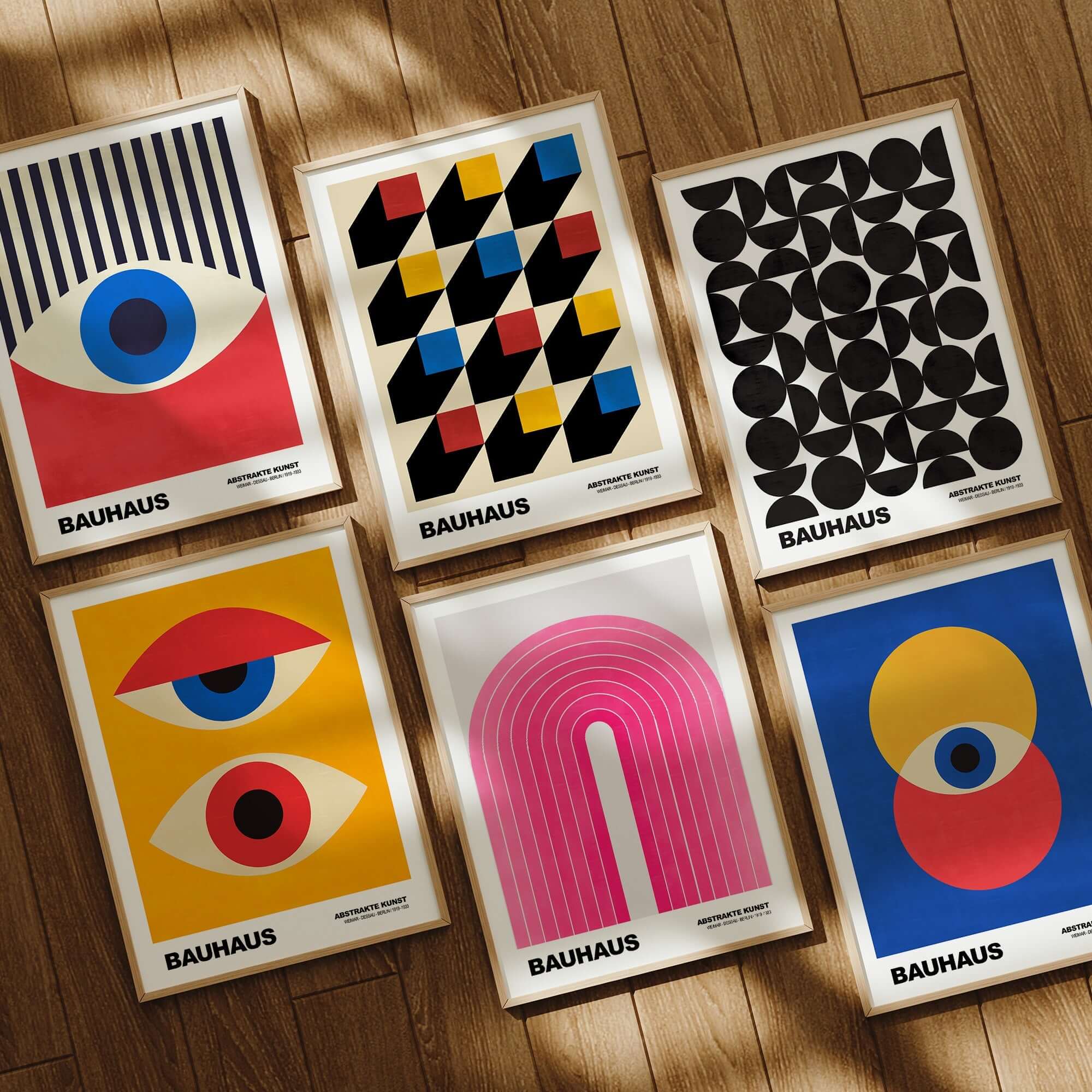 Bauhaus exhibition prints featuring geometric designs, vibrant colors, and modernist art styles arranged on a wooden floor.