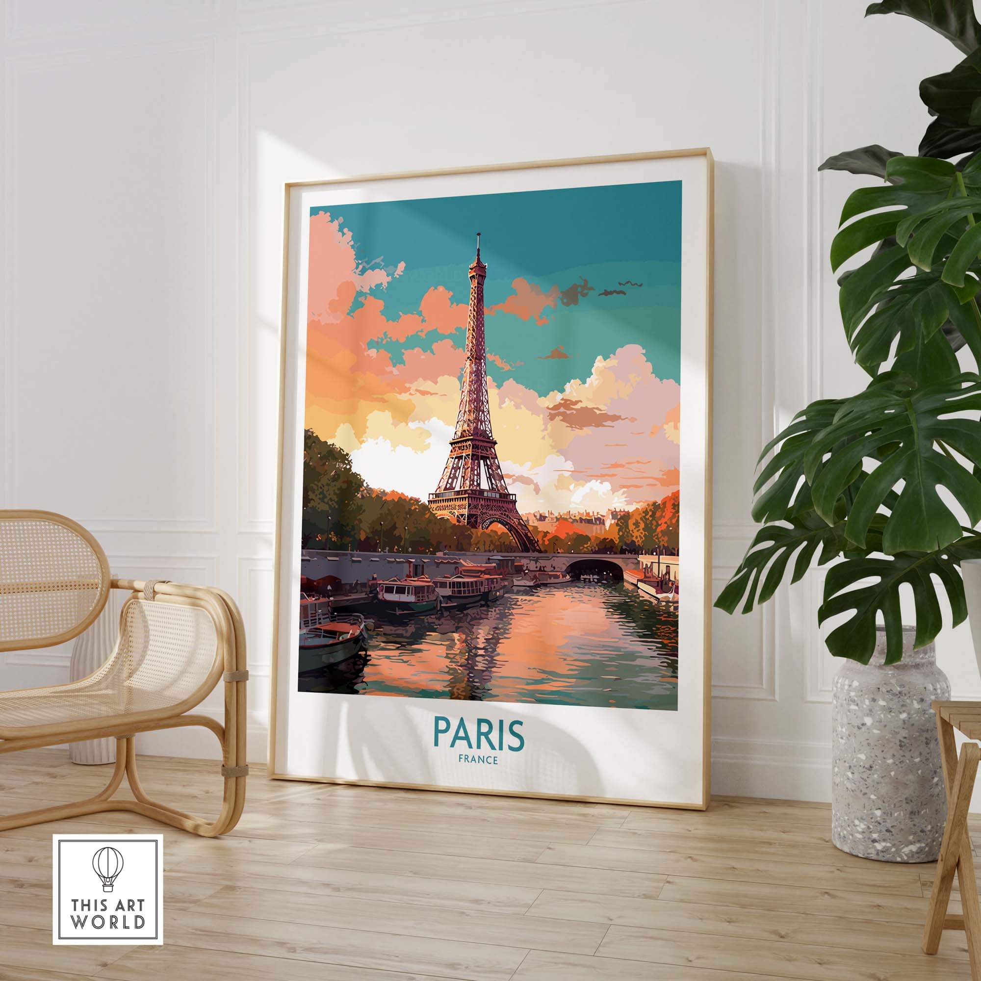 Framed travel poster of Paris featuring the Eiffel Tower at sunset. The frame is resting on the floor next to a cane chair in a boho chic room. 