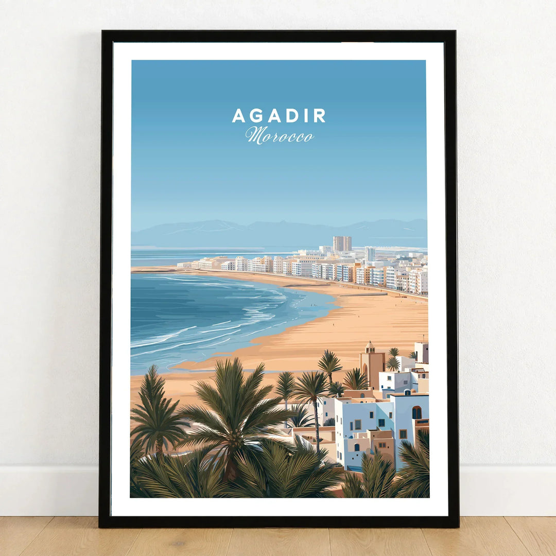 Agadir Morocco Poster – Travel Print in a black wooden frame leaning against a white wall on a light wooden floor