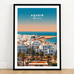 Agadir Travel Poster – City Skyline in a black wooden frame leaning against a white wall on a light wooden floor