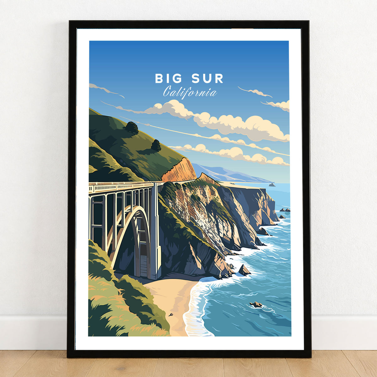 Big Sur Print in a black wooden frame leaning against a white wall on a light wooden floor