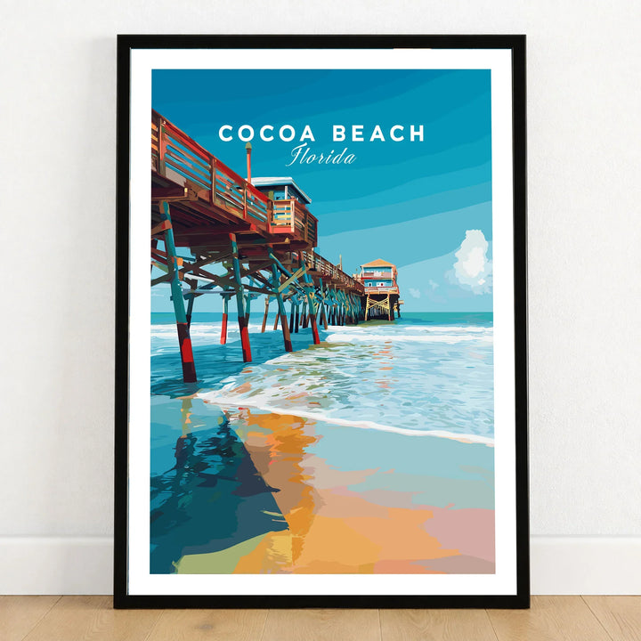 Cocoa Beach Florida Pier Print - Coastal Florida Wall Art in a black wooden frame leaning against a white wall on a light wooden floor