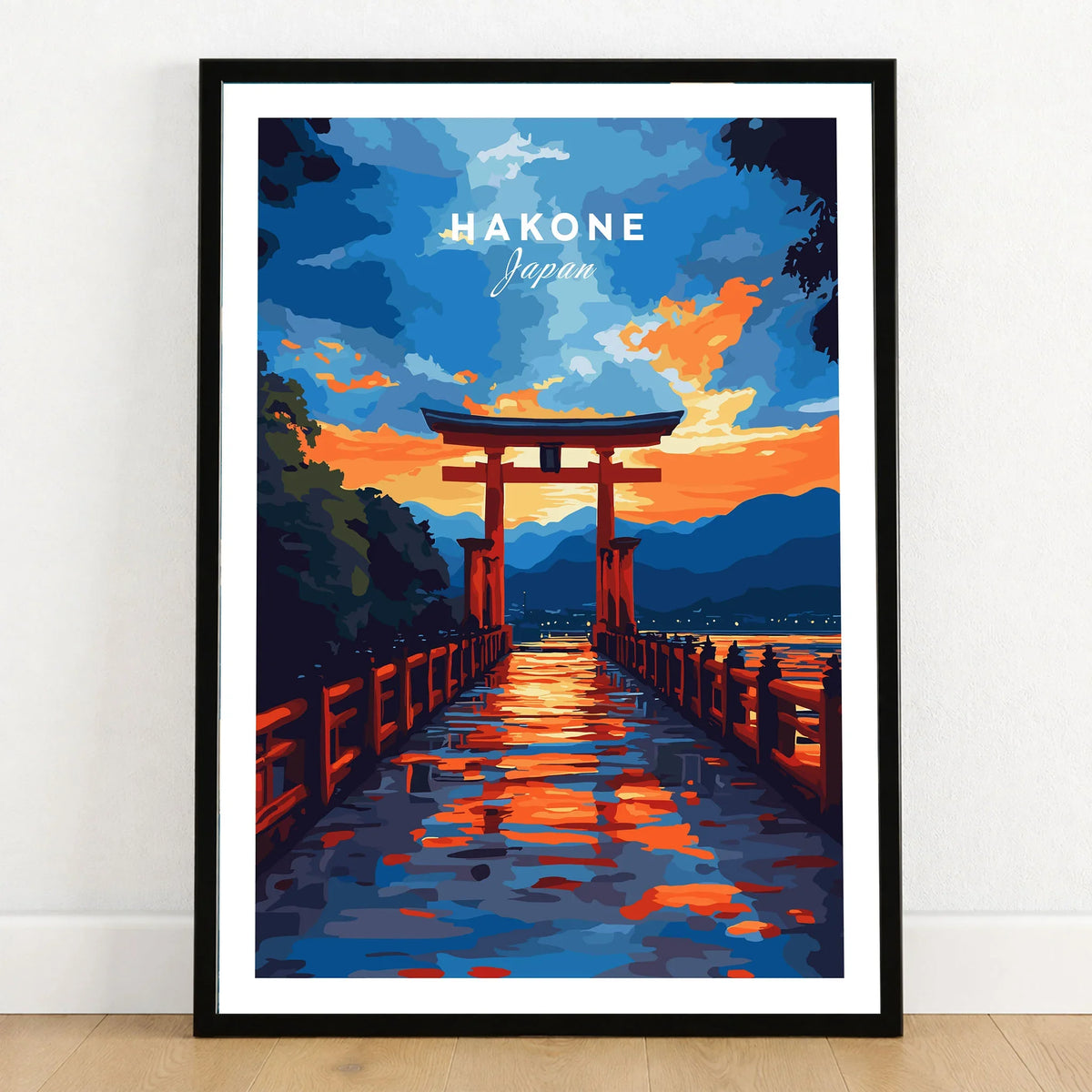 Hakone Wall Art Japan Torii Gate Sunset Reflections Poster - Vibrant Lake Ashi Print in a black wooden frame leaning against a white wall on a light wooden floor