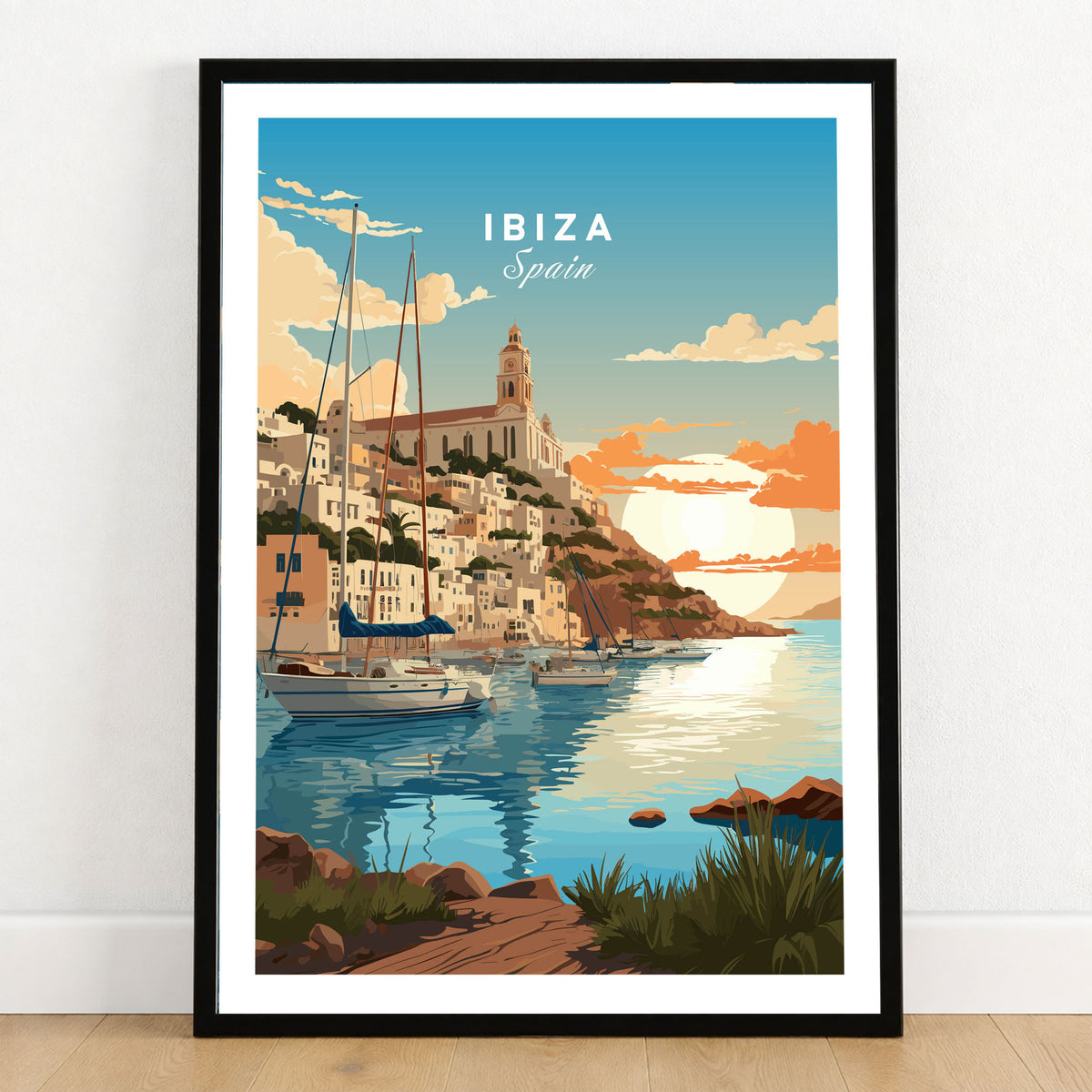 Ibiza Poster Print in a black wooden frame leaning against a white wall on a light wooden floor